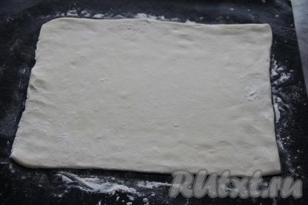 Один пласт слоёного теста слегка раскатать на посыпанной мукой поверхности, затем переложить на противень, застеленный ковриком (или пергаментной бумагой) для выпечки.