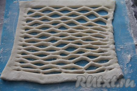 Вторую часть теста также слегка раскатать, затем сделать надрезы рифлёным ножом. Если такого ножа у вас нет, тогда можно просто нарезать тесто на полоски шириной 2-3 сантиметра и выложить сверху на пласт с начинкой в виде решётки.