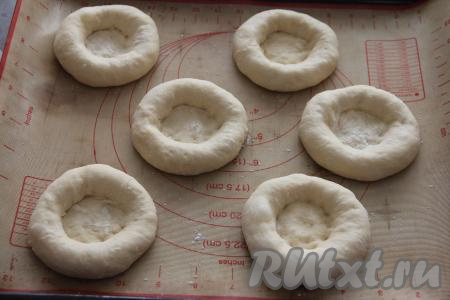 На противень, застеленный ковриком (или пергаментом) для выпечки выложить шарики из теста, руками сформировать заготовки ватрушек с бортиком.