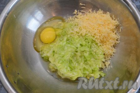 По прошествии 15 минут отжать из натёртого кабачка руками выделившийся сок (отжатый сок нам не понадобится). В миску с кабачковой массой, отжатой от сока, выложить натёртый сыр и сырое яйцо.