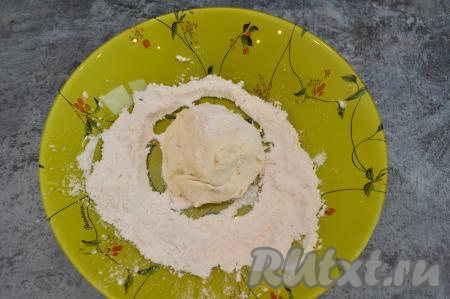 В тарелку всыпать 2 столовых ложки муки. Влажными руками сформировать округлый творожно-банановый сырник и обвалять его со всех сторон в муке.