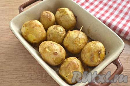 Ставим форму с молодой картошкой в кожуре с чесноком в духовку, прогретую до 180 градусов. Запекаем примерно 35 минут. Готовность можно проверить, проколов картофель зубочисткой или ножом (если картофель легко прокалывается, значит он уже готов). Продолжительность запекания зависит от сорта картошки и величины клубней.