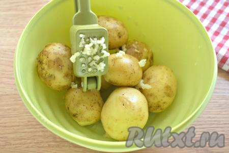 Зубчики чеснока очищаем, пропускаем через пресс (или натираем на мелкой тёрке) и выкладываем к картофелю.