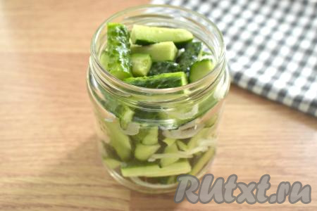 Далее банку заполняем огурцами вперемешку с оставшимся луком и чесноком. Стараемся забить банку плотно.