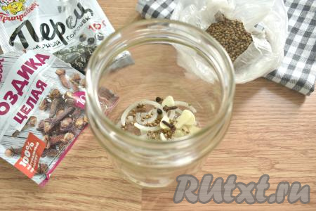 На дно простерилизованной банки (я предпочитаю стерилизовать банку над паром) выкладываем небольшое количество лука и чеснока, добавляем гвоздику, перец горошком и кориандр.