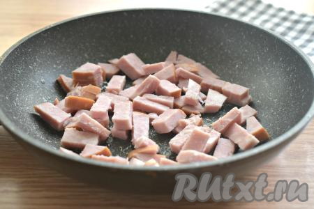 На сковороде разогреваем растительное масло, выкладываем ветчину, нарезанную на брусочки, и обжариваем минут 5, периодически помешивая. Если ветчина очень жирная, тогда её можно обжаривать без добавления масла.