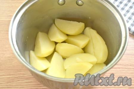 Очищаем картошку, разрезаем её на 2-4 части, перекладываем в кастрюлю, заливаем водой, солим, ставим на сильный огонь, а после закипания варим на небольшом огне до готовности (минут 25). Когда картофель сварится до готовности (будет легко прокалываться вилкой), убираем его с огня, полностью сливаем воду.