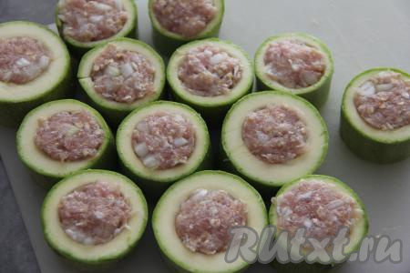 Выложить колечки из кабачка на разделочную доску и наполнить их фаршем.