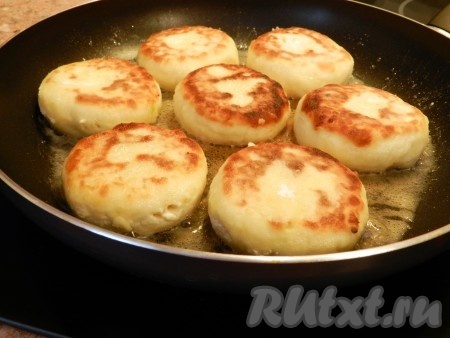 Когда сырники обжарятся до румяности с двух сторон, уменьшить огонь до минимального, перевернуть сырники, накрыть сковороду крышкой и готовить ещё 5 минут. За это время ещё 1 раз перевернуть сырники.