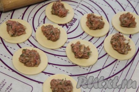 Выложить на каждый кружочек, примерно, по 1 чайной ложке начинки из говядины. Тесто, оставшееся после вырезания кружочков, тоже раскатать, вырезать из него кружочки и выложить начинку.