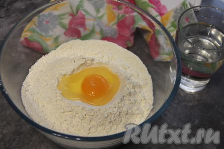 В центр миски поверх муки добавить яйцо и холодную воду.