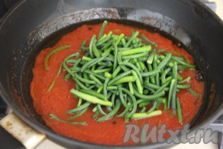 Стрелки чеснока нарезать на кусочки длиной примерно 3-4 сантиметров, выложить в сковороду с закипевшей томатной смесью, перемешать.