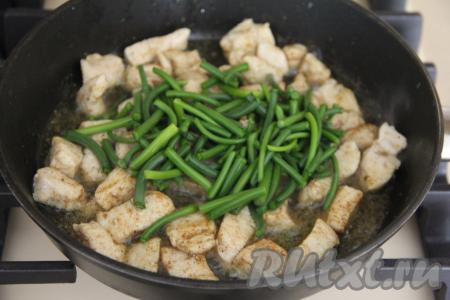 Чесночные стрелки нарезать на кусочки длиной 3 сантиметра и выложить в сковороду с обжаренным мясом курицы, перемешать.