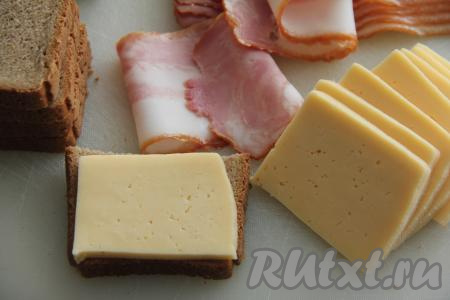 На хлеб выложить сыр, а затем завернуть хлеб с сыром в полоски бекона.