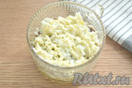 Яйца разделяем на белки и желтки. Сейчас нам потребуются только белки, натираем их на крупной тёрке, раскладываем поверх рыбы и покрываем майонезом.