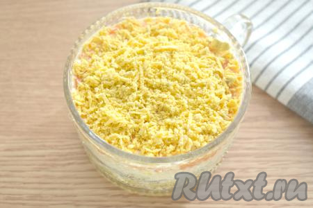 По традиции завершающим слоем салата "Мимоза" будет желток. Измельчаем его вилкой в крошку и выкладываем последним слоем.