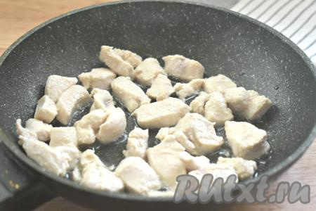На сковороду вливаем растительное масло и разогреваем его. В горячее масло выкладываем нарезанное куриное мясо и, периодически перемешивая, обжариваем на достаточно сильном огне 5 минут.