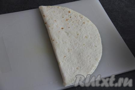 Чистой половиной лепёшки накрыть половину тортильи с начинкой и слегка прижать.