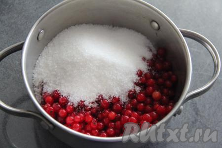 Прежде всего нужно сварить ягодную начинку для слоёного пирога. Если красная смородина заморожена, её нужно немного разморозить, а воду, выделившуюся в процессе размораживания ягодок, нужно слить. Свежую красную смородину нужно перебрать, убирая листья, веточки и испорченные ягоды, затем хорошо промыть, выложив в сито и оставить на несколько минут, чтобы с ягод стекла лишняя вода. В кастрюле соединить 300 грамм подготовленной красной смородины, добавить сахар, перемешать и поставить на средний огонь.