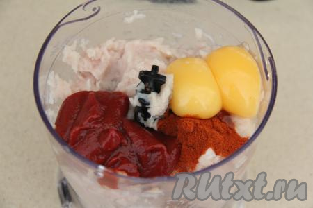 В чашу измельчителя поместить куриное филе, нарезанное на части, яичные желтки, соль, кетчуп (или томатный соус), специи (у меня - паприка), лук, разрезанный на части, и чеснок.
