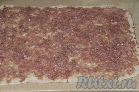 Выложить фарш на лист лаваша и равномерно размазать по всей поверхности тонким, однородным слоем.