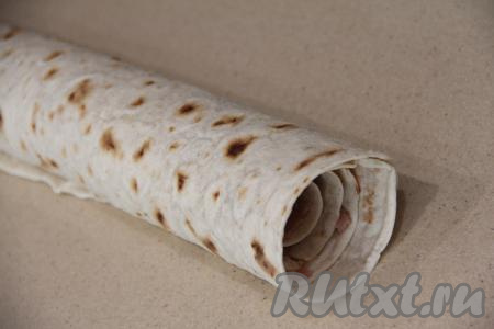 Свернуть лаваш с фаршем в тугой рулет, начиная с узкой стороны.