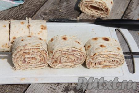 Нарезать рулет на кусочки шириной примерно 3 сантиметра (у меня получилось 9 рулетиков). Надеть рулетики на шампуры. Я надела на каждый шампур по 3 рулетика. В результате у меня получилось 3 шампура с рулетиками.