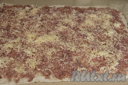 Поверх фарша равномерно разложить натёртый на мелкой тёрке сыр.
