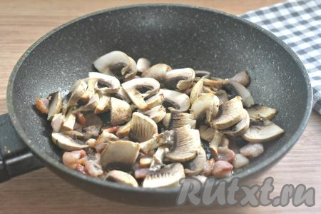 К обжаренному бекону выкладываем шампиньоны, нарезанные на пластины, перемешиваем и обжариваем 5 минут, время от времени помешивая.