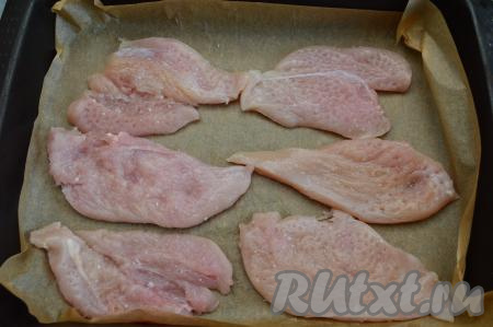 Противень застелить пергаментной бумагой (или фольгой), затем выложить куриные отбивные, посолить их по вкусу.