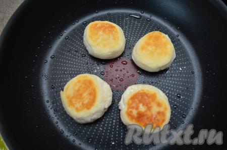 Затем сырники перевернуть, сделать огонь ниже среднего, накрыть сковороду крышкой и жарить ещё 2-3 минуты. После этого огонь выключить и оставить сырники в сковороде под крышкой на 2-3 минуты.