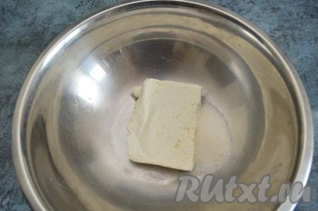 В глубокую миску выложить творог, всыпать к нему сахар.