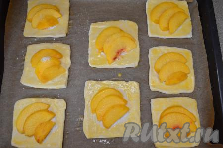 Яичный желток взбить вилкой в небольшой ёмкости. Смазать тесто, не прикрытое персиками, взбитым желтком и отправить противень в духовку, разогретую до 180 градусов. Выпекать слойки с персиками минут 20-25 (до золотистости теста).