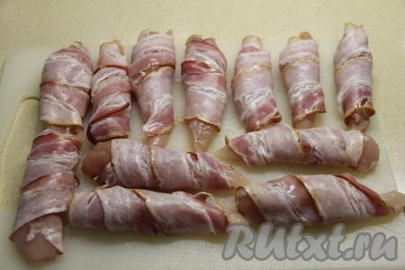 Каждый брусочек филе посолить и обернуть в полоску бекона.