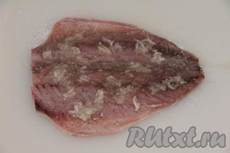 Затем поверх филе равномерно разложить измельчённый чеснок.