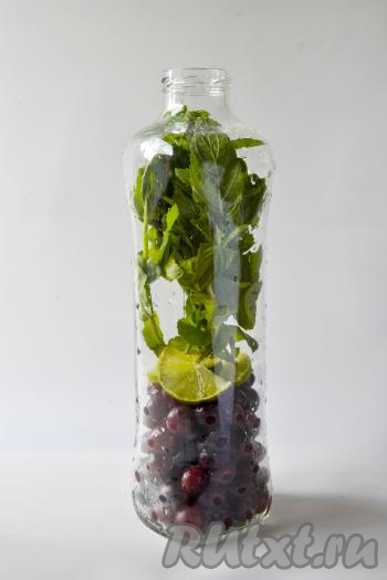 Бутылку (или банку) объёмом 1 литр промойте горячей водой с содой, простерилизуйте над паром (или в духовке, или в микроволновке). Крышку прокипятите 2-3 минуты с момента закипания воды. В бутылку (или банку) насыпьте крыжовник, выложите кружочки лайма и веточки мелиссы.