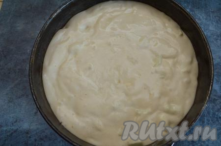 Форму для выпечки (я взяла разъёмную форму диаметром 23 сантиметра) застелите пергаментом, смажьте бока и низ формы небольшим кусочком сливочного масла. Переложите в форму бисквитное тесто, смешанное с яблоками.