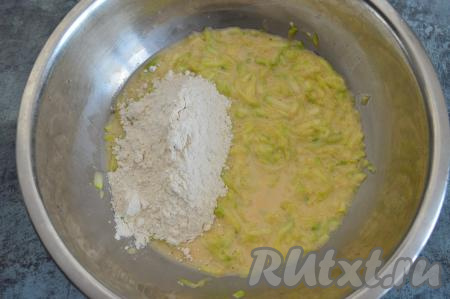 В миску со смесью яиц и молока добавить кабачковую массу, отжатую от лишнего сока, перемешать. Всыпать половину муки, тщательно перемешать ложкой.