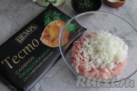 Разморозить слоёное тесто при комнатной температуре. Мясо (у меня - куриное филе) вымыть, обсушить, пропустить через мясорубку и переложить в объёмную миску. Для приготовления слоёных пирожков можно взять и покупной фарш. Лук почистить, мелко нарезать, выложить к фаршу.