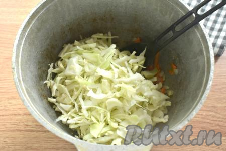 К обжаренным моркови с луком выкладываем капусту, нарезанную на тонкие полоски, перемешиваем и обжариваем под крышкой 7 минут, время от времени перемешивая.