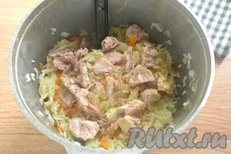 К тушёной капусте и рису добавляем кусочки тушёнки без жира, перемешиваем, готовим 5-7 минут под крышкой и убираем с огня.