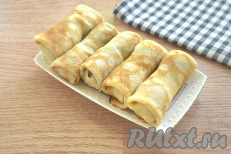 Сворачиваем блинчик с сосиской в форме конвертика (то есть вначале с двух сторон подворачиваем края блина на сосиску, а затем сворачиваем в рулет, начиная со стороны с сосиской). Аналогично формируем все блинчики, фаршированные сосисками.