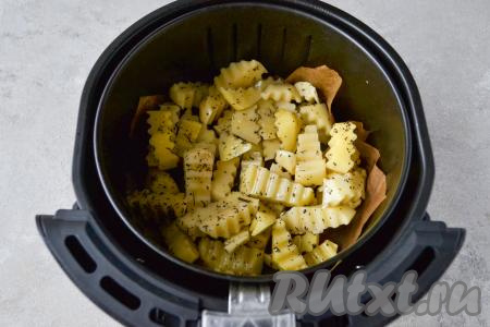 Включите аэрогриль в сеть. Установите температуру 200 градусов и время 10 минут, это нужно сделать для нагрева прибора. Через 10 минут, когда прибор разогреется, застелите чашу аэрогриля пергаментной бумагой. Я застилаю чашу для того, чтобы потом её легче было мыть. Сделайте в бумаге ножом несколько проколов, затем выложите ломтики картофеля в чашу. Поставьте чашу с картошкой в аэрогриль, крышку закройте, установите температуру 200 градусов, время - 20 минут.