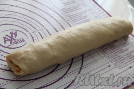 Свернуть тесто с персиковой начинкой в плотный рулет, начиная с широкой стороны, и защипать край теста.