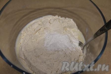 Добавить соль, разрыхлитель и половину муки, перемешать ложкой.