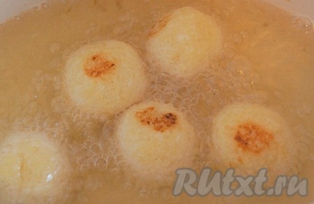 Сформировать из творожного теста влажными руками небольшие шарики. Благодаря влажным рукам, шарики получатся более ровными и гладкими. В глубокой сковороде (или в кастрюле с толстым дном) хорошо разогреть растительное масло. Затем выложить несколько творожных шариков (масло должно, как минимум, на половину покрывать шарики). Жарить на среднем огне до равномерно золотистого цвета со всех сторон.