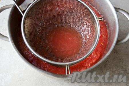 По истечении 4-5 часов мякоть будет сверху, а внизу будет много сока. При помощи сита с мелкой решёткой и половника удалите лишний сок с томатной массы. Для этого опустите сито в кастрюлю с измельчёнными томатами как можно ближе ко дну, а сок, который будет собираться в сите, вычерпайте половником.
