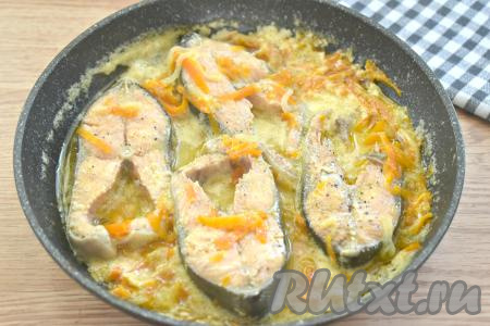 После закипания соуса из сметаны убавляем огонь до ниже среднего, накрываем сковороду крышкой и тушим горбушу с луком и морковью 20 минут.