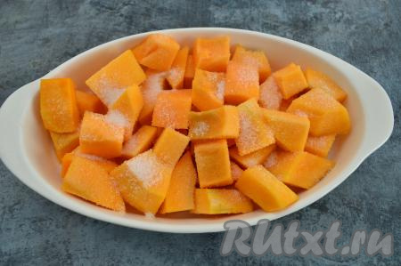 Тыкву очистить от кожуры и волокон с семенами. Нарезать 600 грамм очищенной тыквы на кусочки размером 3 на 4 сантиметра. В форму для запекания (я решила запекать в форме размером 26 на 16 сантиметров) налить 2-3 столовых ложки воды и выложить в неё кусочки тыквы. Посыпать тыкву сахаром, перемешать. У меня тыква была достаточно сладкая, поэтому двух столовых ложек сахара мне вполне хватило.