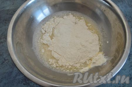 В получившуюся смесь всыпать половину муки, перемешать столовой ложкой. Затем частями начать добавлять оставшуюся муку, хорошо вмешивая её руками в пельменное тесто. Как только тесто перестанет липнуть к рукам, больше муку не добавляйте. Затем вымесить тесто в течение 2-3 минут.